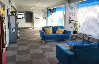Stewart & Wisbey customer lounge with blue sofas, yellow cushions, blue armchairs and checkerboard carpet